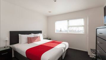 Relax in a spacious room with a large bed, bedside table, and wardrobe.