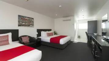 Quarto de hotel com duas camas, uma escrivaninha e uma televisão.