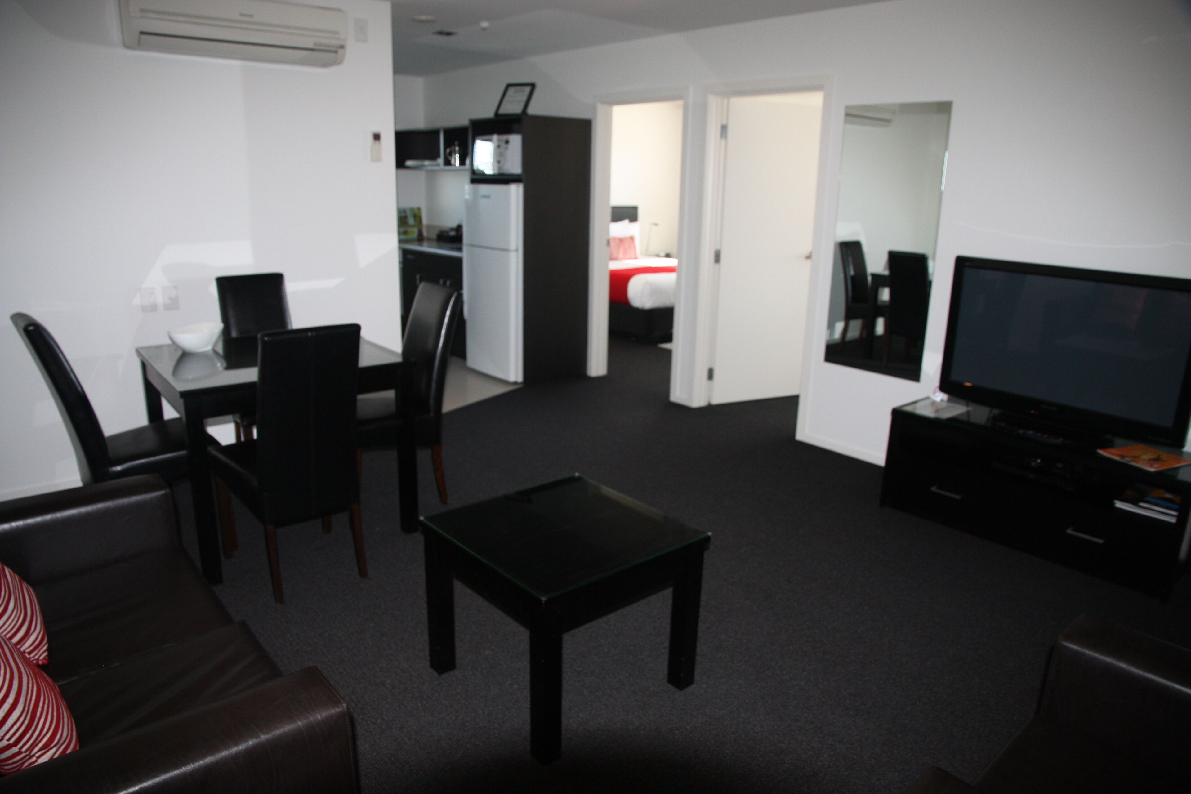 A compact living space with a dining area, a kitchenette, a bedroom, and a TV.