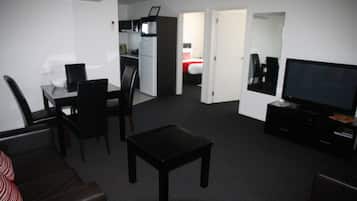 A compact living space with a dining area, a kitchenette, a bedroom, and a TV.