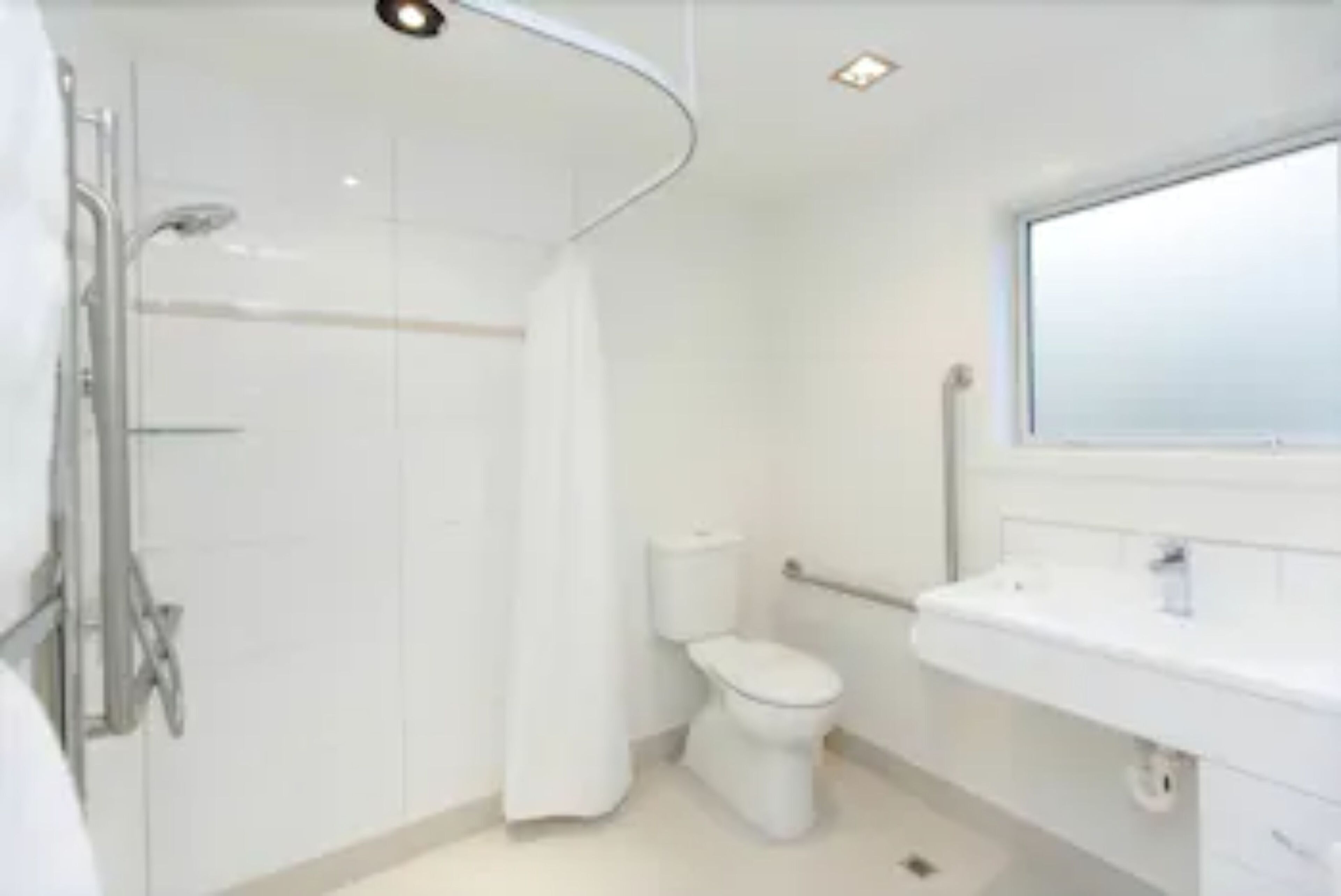Een badkamer met douche, toilet en wastafel.