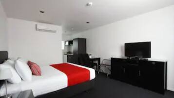 Una habitación de hotel moderna con una cama grande, un escritorio, un televisor y un armario.