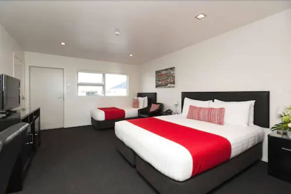 Una habitación de hotel moderna con una cama grande, un escritorio, un televisor y una ventana.
