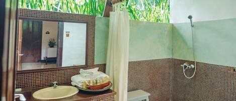 A bathroom with a sink, mirror, shower, and a small stool.