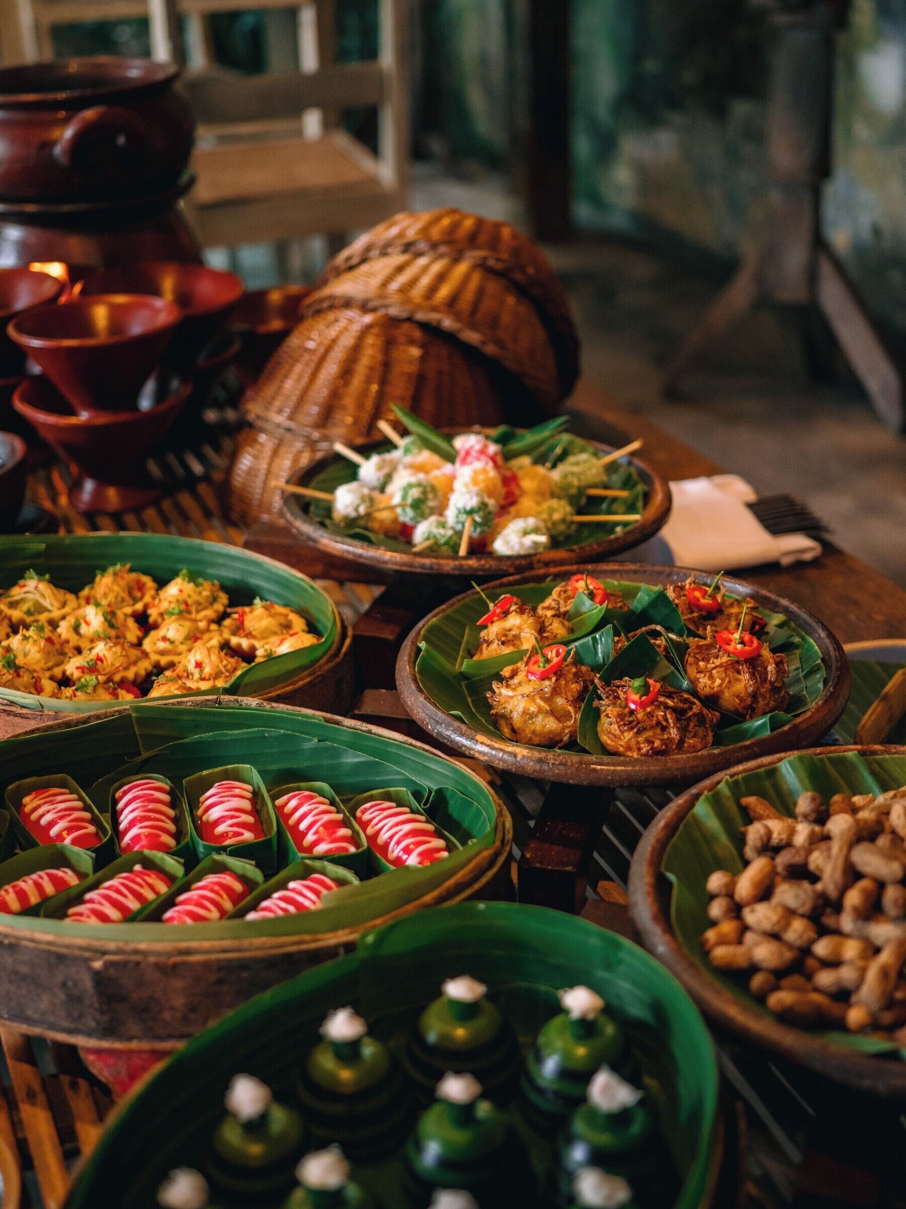A variety of dishes served in traditional clay pots and banana leaves, suggesting a cultural or traditional dining experience.