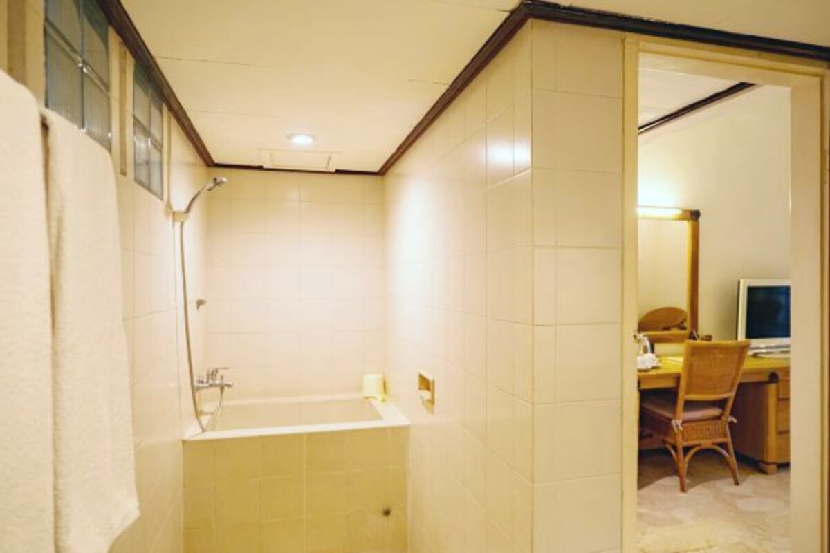 Un baño con bañera, ducha y un escritorio con silla.