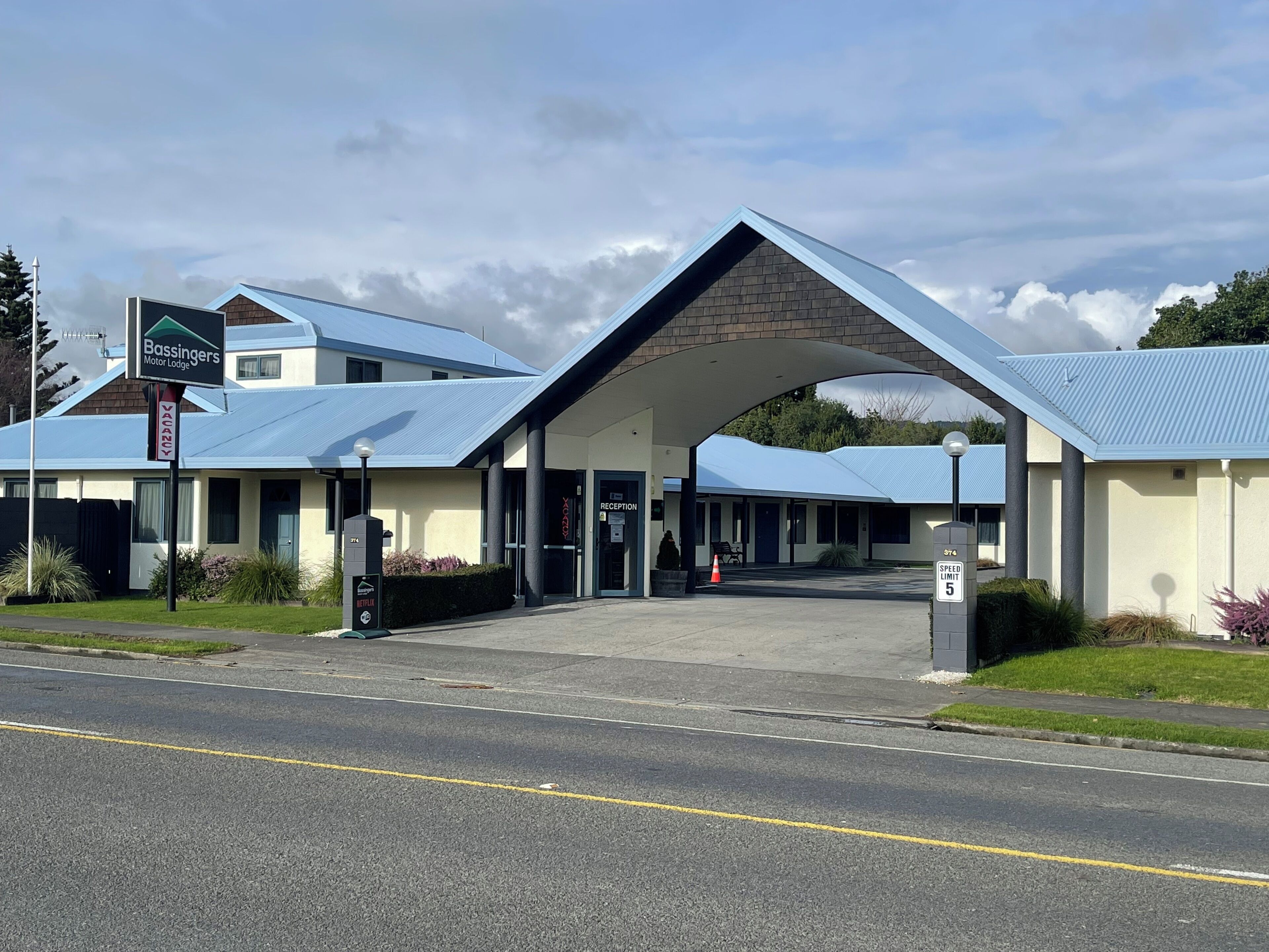A building with a blue roof and a sign indicating it is a motor lodge.