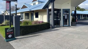Un motor lodge Bassingers con una zona de recepción, un letrero que anuncia Wi-Fi gratuito y una entrada ajardinada.