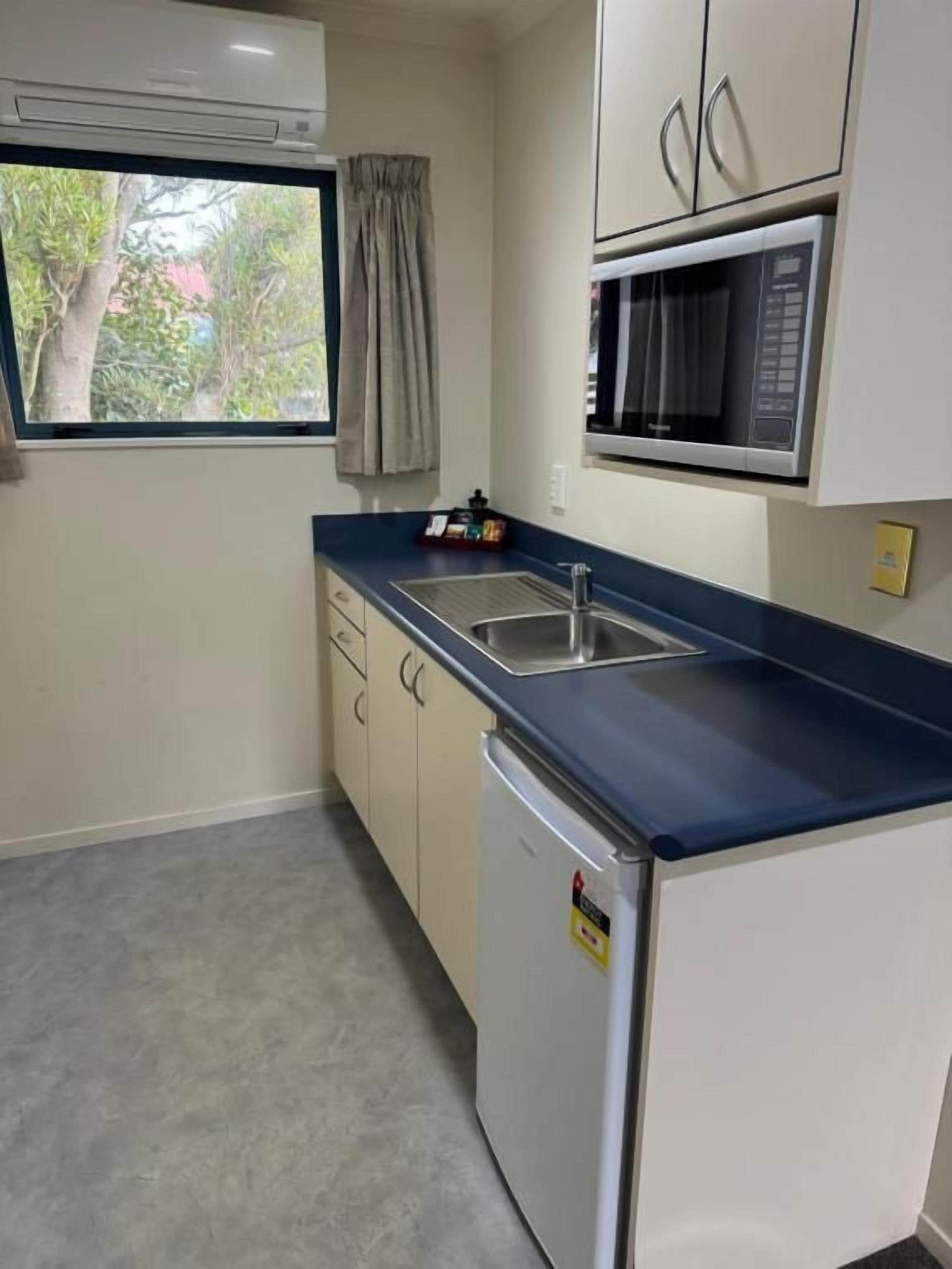 Cocina compacta con microondas, lavabo y un refrigerador pequeño.