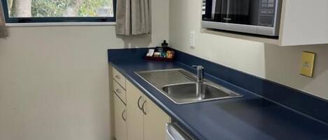 Cocina compacta con microondas, lavabo y un refrigerador pequeño.