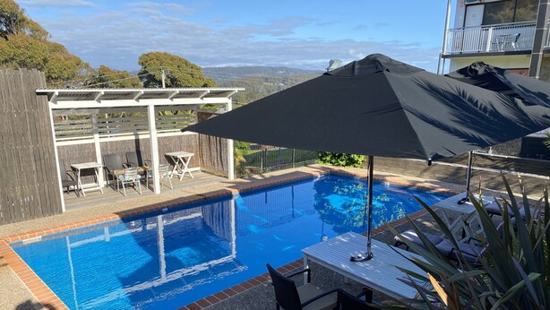 A backyard with a swimming pool, outdoor furniture, and a pergola. - Top of the Town Motel Narooma (Narooma)