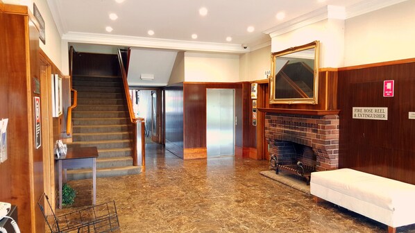 A hotel lobby with a marble floor, a staircase, a fireplace, and a bench.