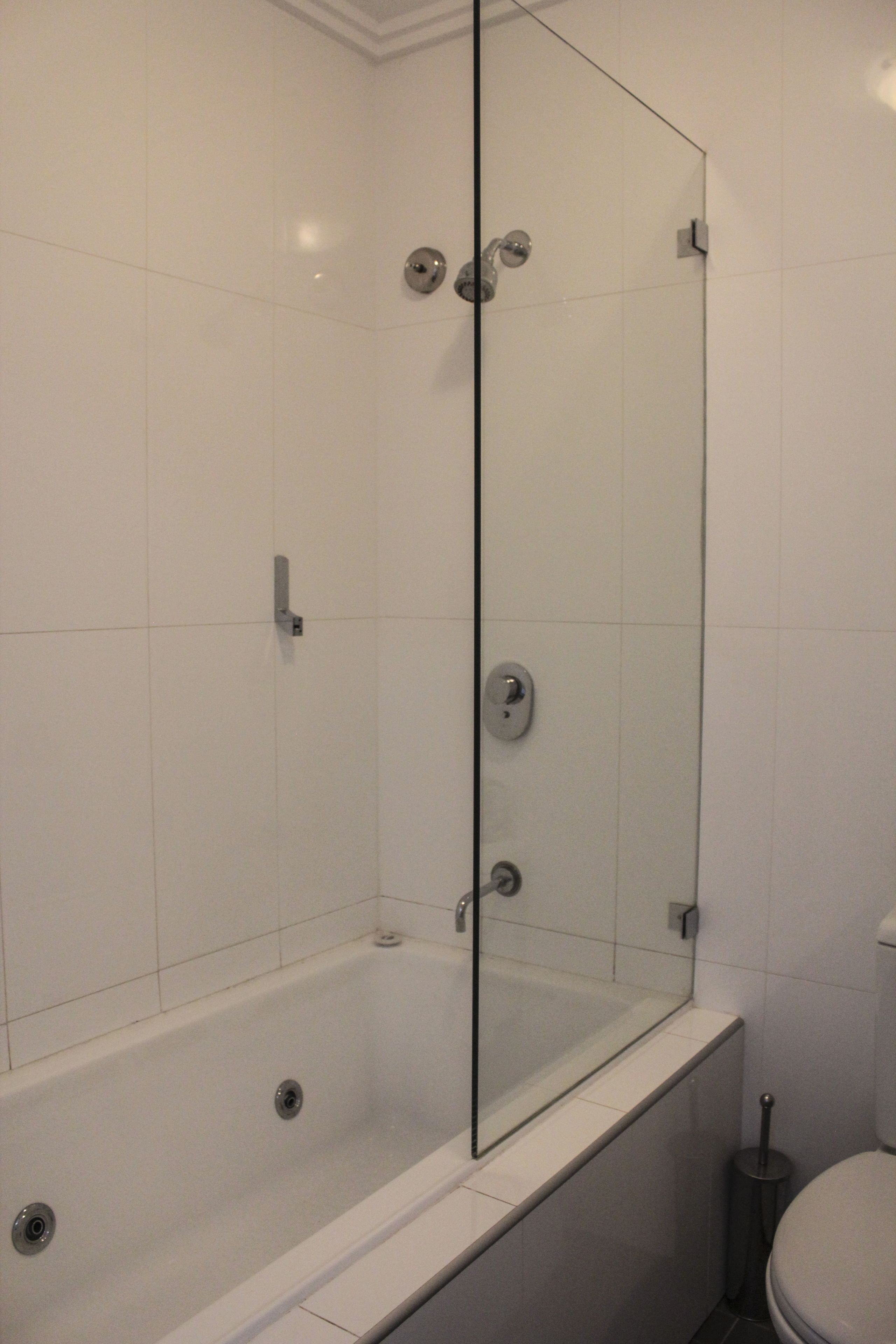Une salle de bain moderne avec une douche à parois de verre, une baignoire blanche et des toilettes.