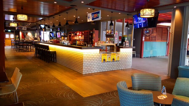 Eine Bar mit einer Theke, Sitzgelegenheiten und einem Fernsehbildschirm.