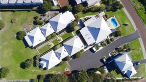 An aerial view of a residential area with multiple houses featuring pitched roofs, a swimming pool, and a parking lot. - Surfpoint Resort (Gnarabup)