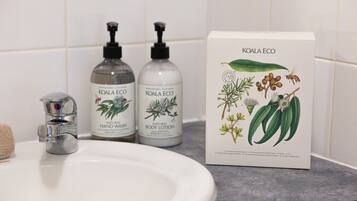 Un lavamanos con dos botellas de Koala Eco para lavado de manos y loción corporal, y una caja con ilustraciones botánicas.