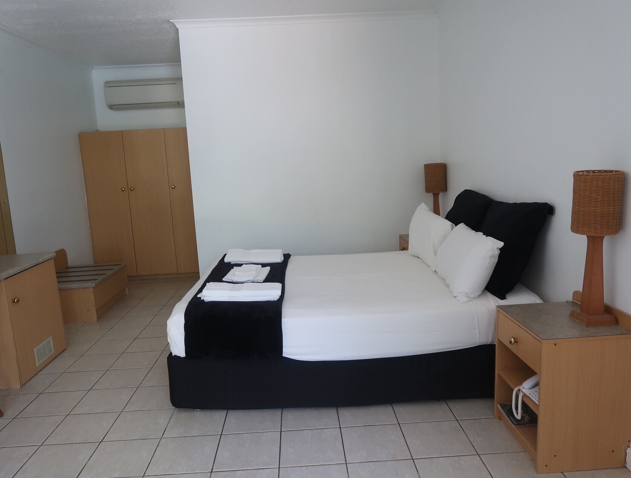 A neatly arranged bedroom with a bed, bedside tables, a wardrobe, and a lamp.