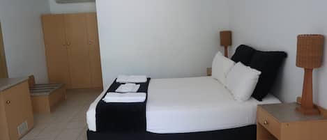 A neatly arranged bedroom with a bed, bedside tables, a wardrobe, and a lamp.