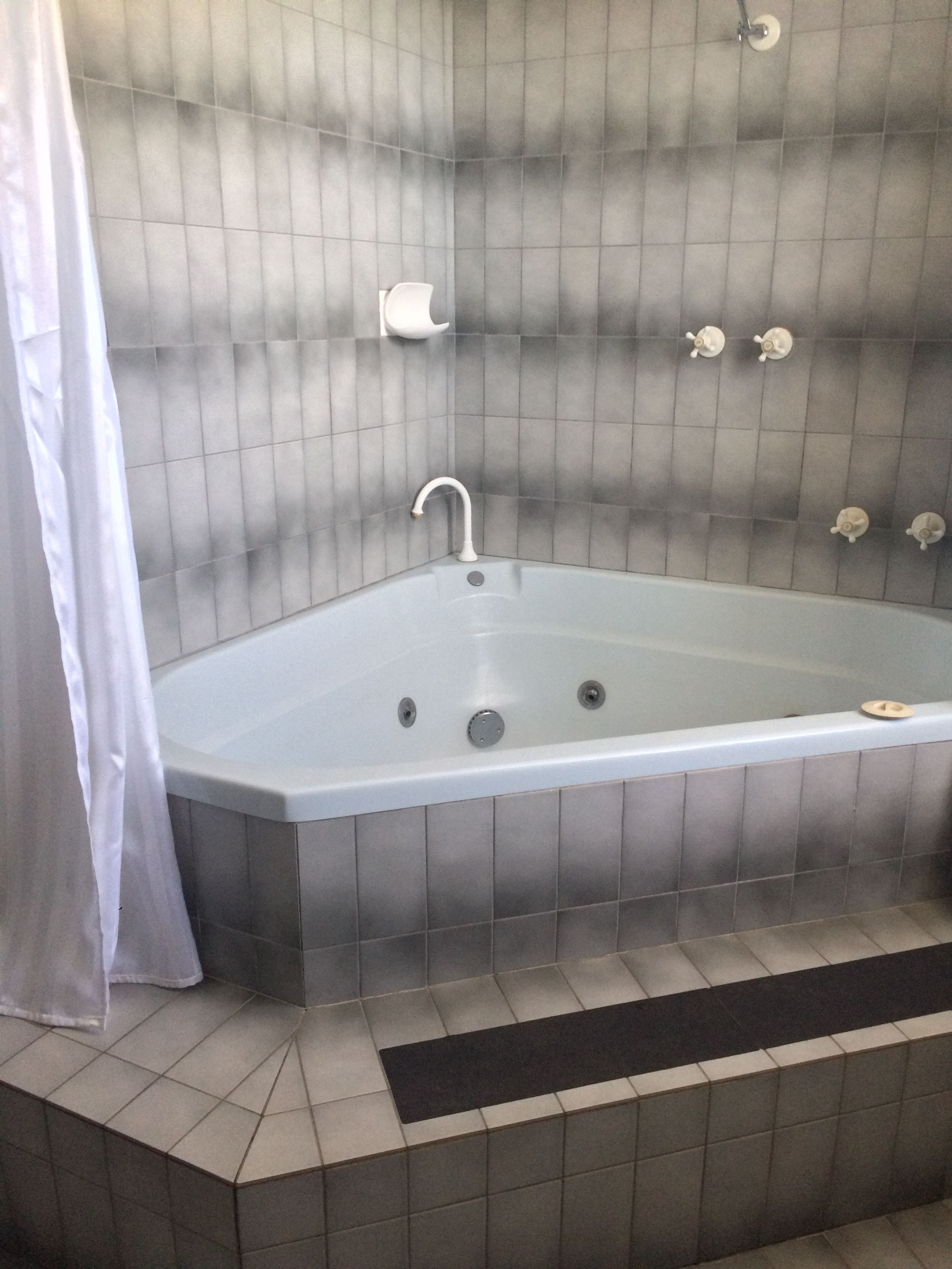 Une salle de bain moderne avec une baignoire sur pieds, un rideau de douche et un carrelage au sol.