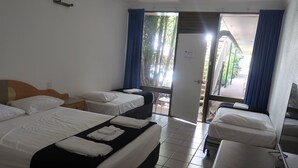 Une chambre d’hôtel avec deux lits, un bureau et une fenêtre avec des rideaux.