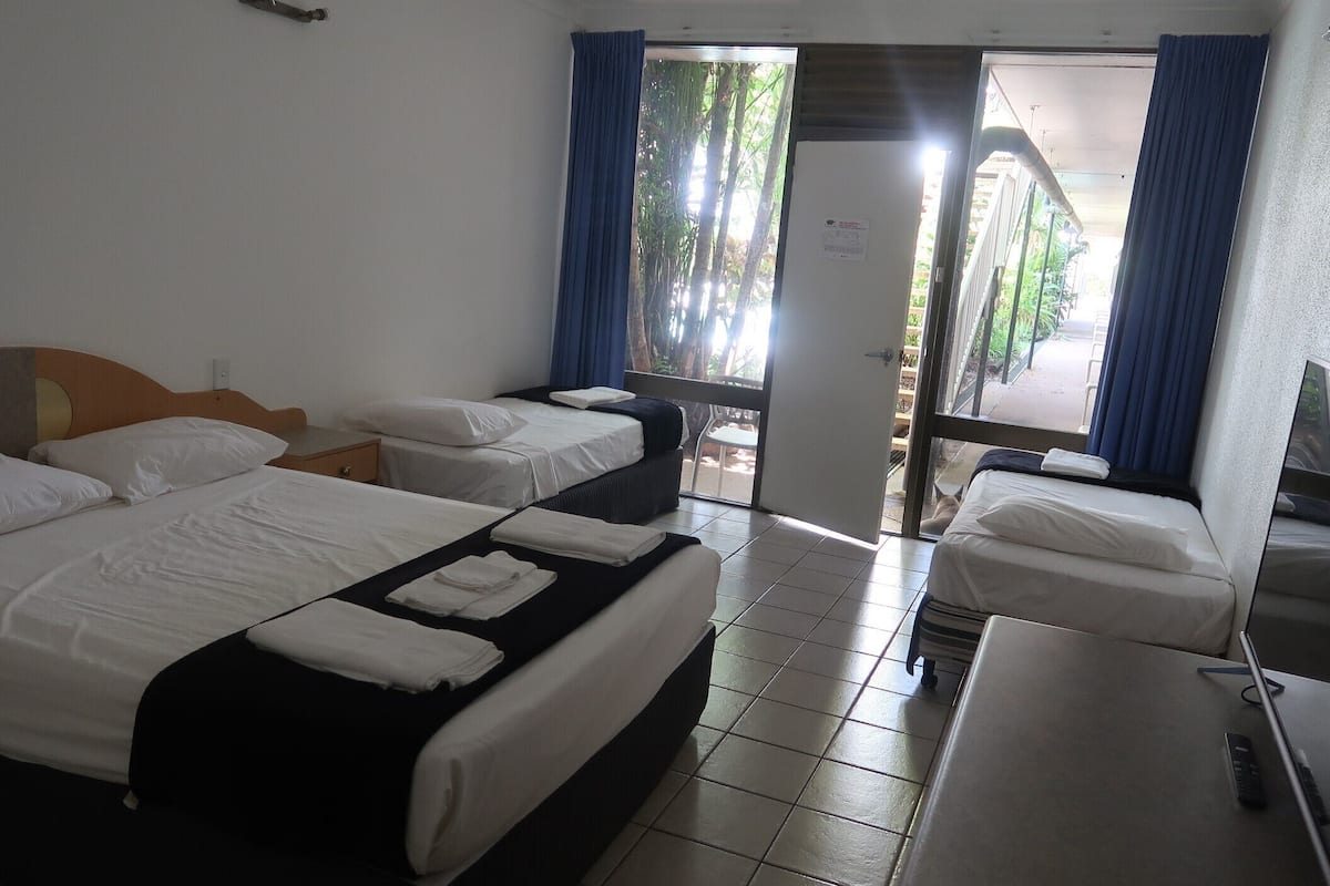 Ein Hotelzimmer mit zwei Betten, einem Schreibtisch und einem Fenster mit Vorhängen.