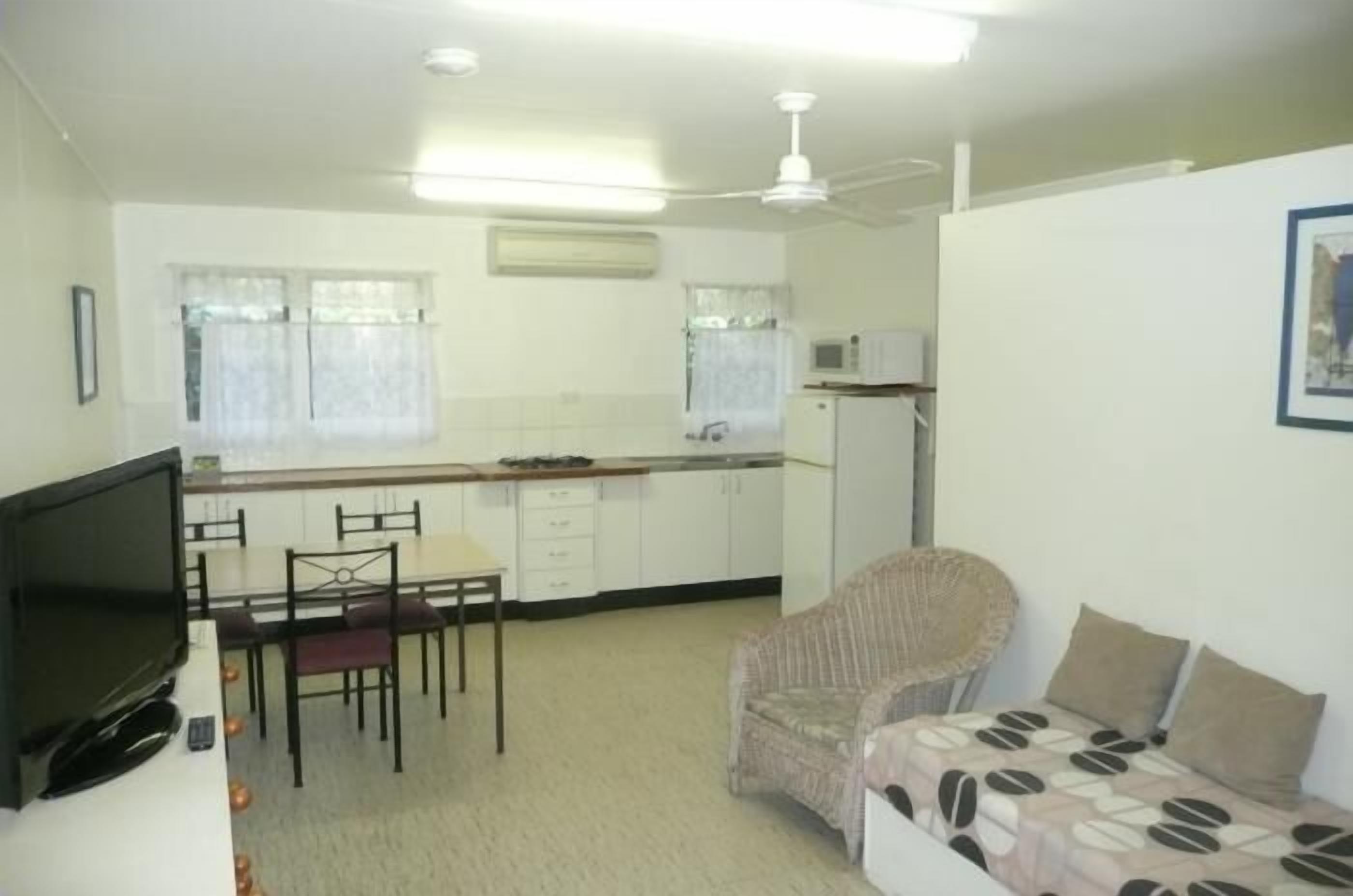 A compact room with a kitchenette, a dining area, and a sofa.