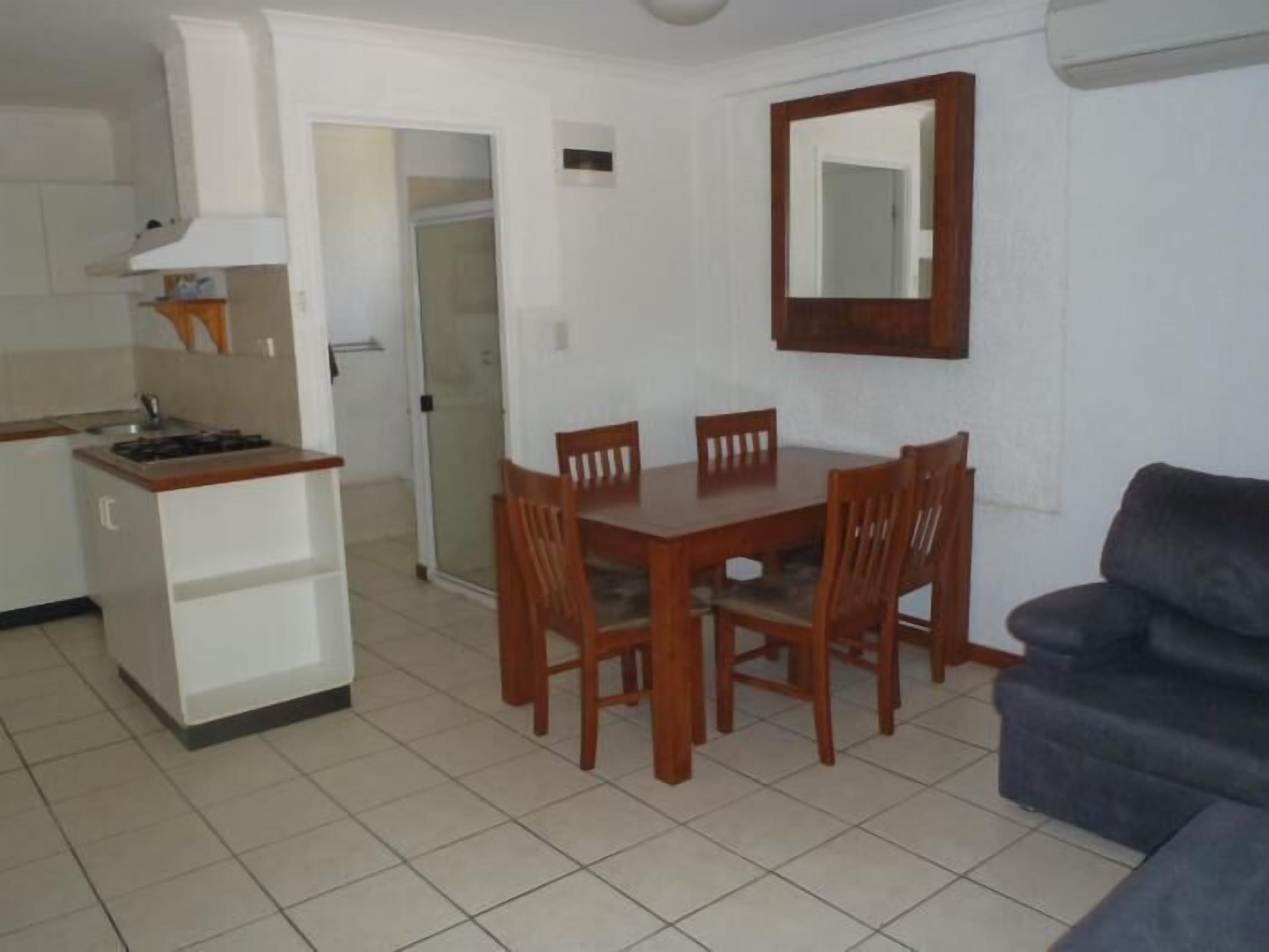 Een ruimtelijke leefruimte met een kitchenette, eettafel en zithoek.