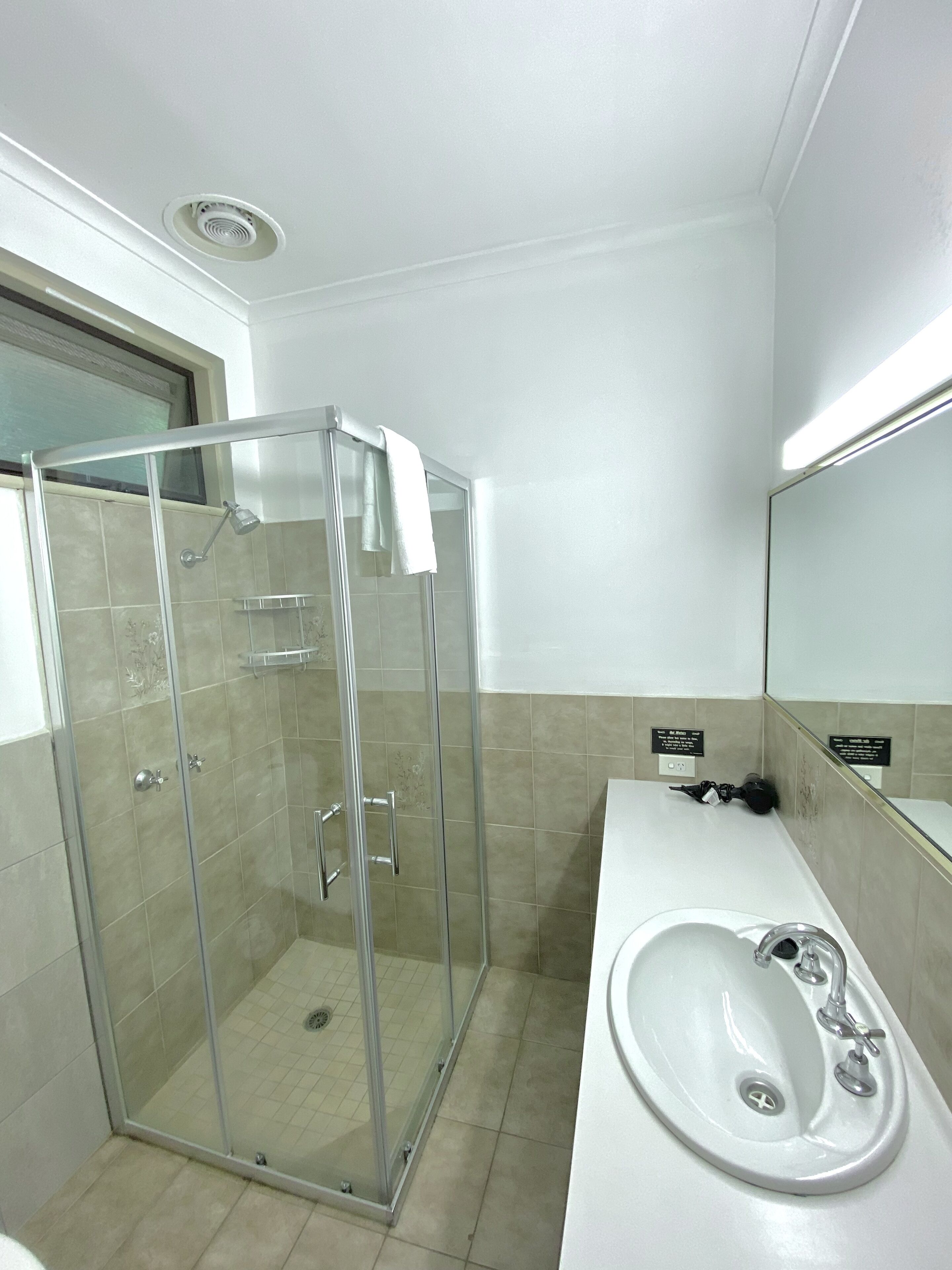 A modern bathroom with a glass-enclosed shower, a white sink, and a mirror above it.