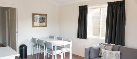 Un salon moderne avec une table à manger, un canapé gris et une fenêtre avec des rideaux.