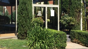 A building entrance with a 'KEEP DOOR CLOSED' sign, surrounded by well-maintained hedges and tall trees. - Ballarat Colonial Motor Inn & Apartments (Warrenheip)