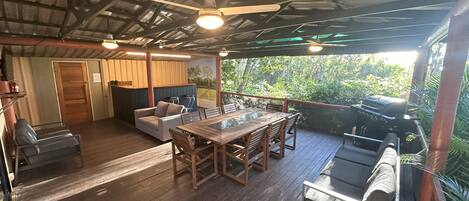 Un patio al aire libre con mesa y sillas de madera, un sofá y una parrilla.