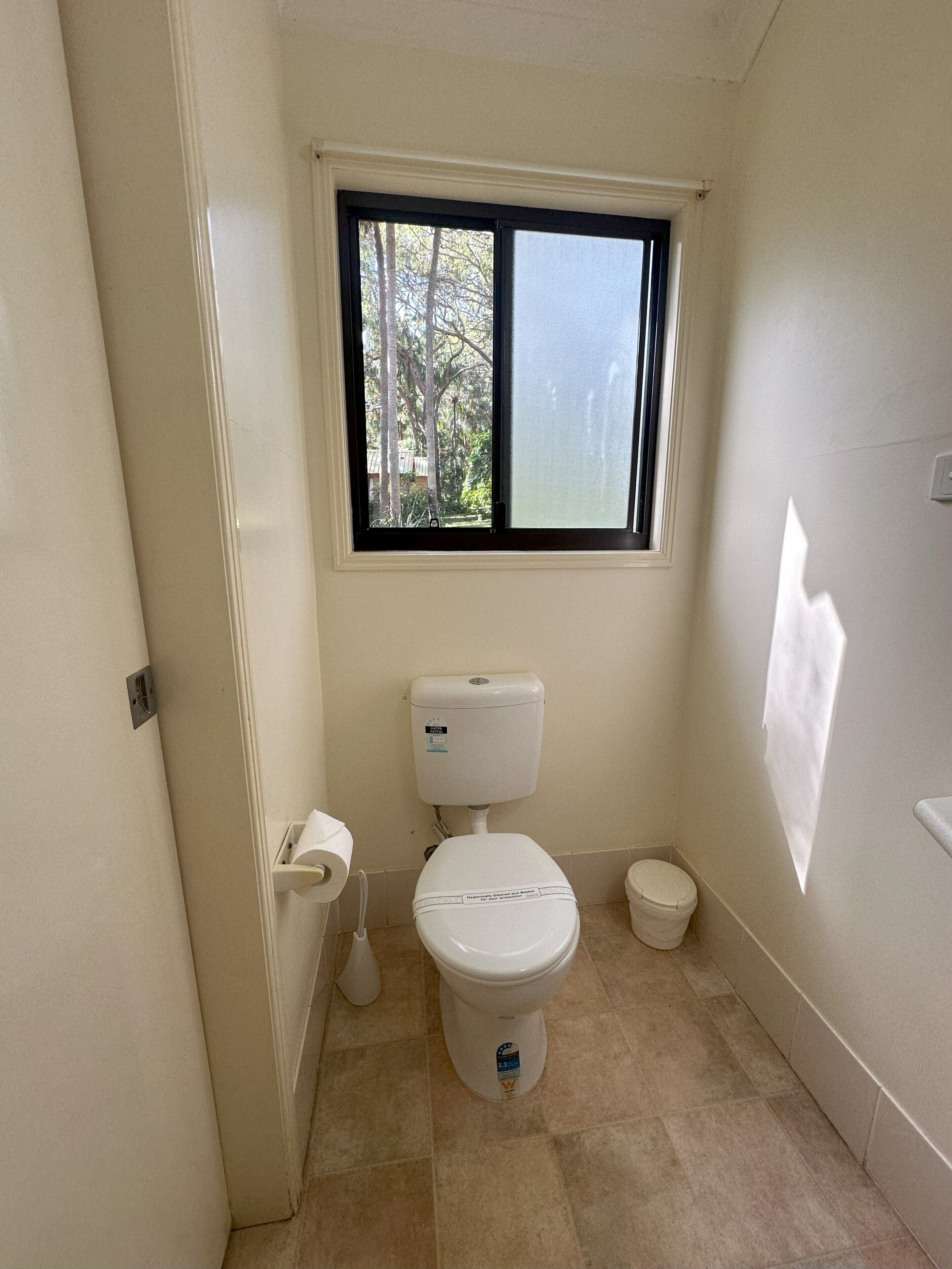 A small, clean bathroom with a toilet, bidet, and a window.