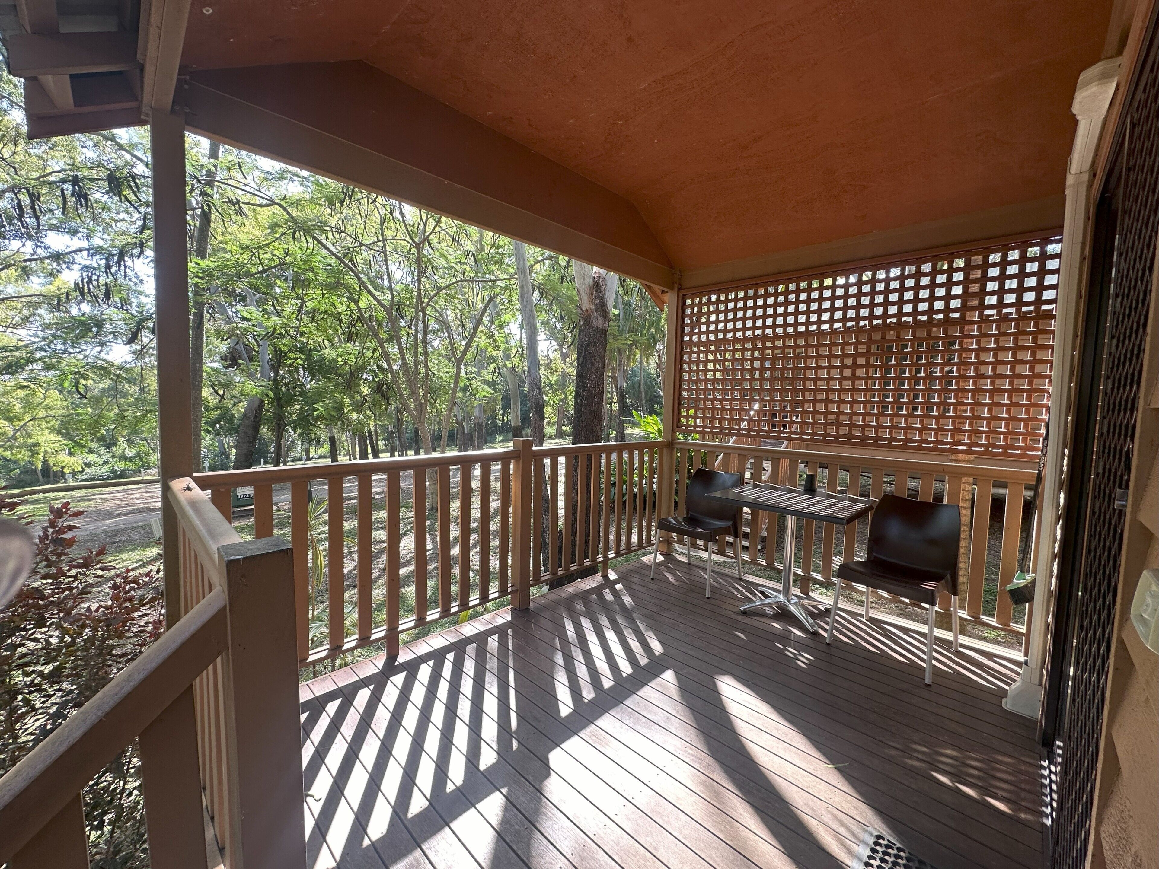 Un espacio exterior techado con terraza de madera, una parrilla y una zona de estar.