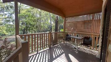 Un espacio exterior techado con terraza de madera, una parrilla y una zona de estar.