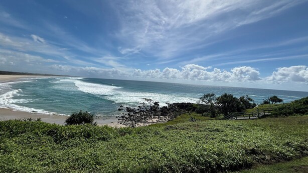 Un paysage côtier avec une plage, des vagues et un ciel dégagé.