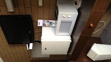A compact kitchenette with a microwave, a small refrigerator, and a black television.