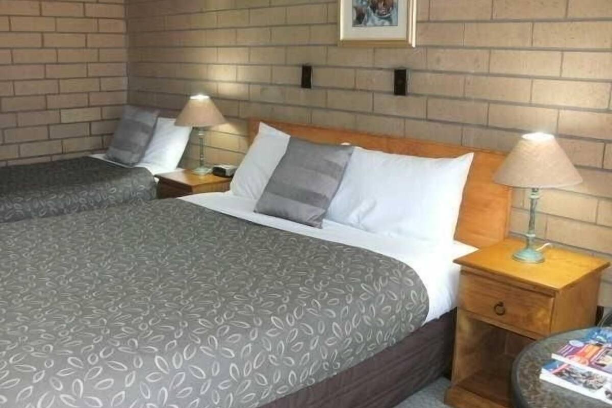 A hotel room with a large bed, two bedside tables, and a small round table with magazines.
