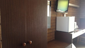 A room with a wooden wardrobe, a television mounted on the wall, and a white refrigerator. - Rippleside Park Motor Inn (Drumcondra)
