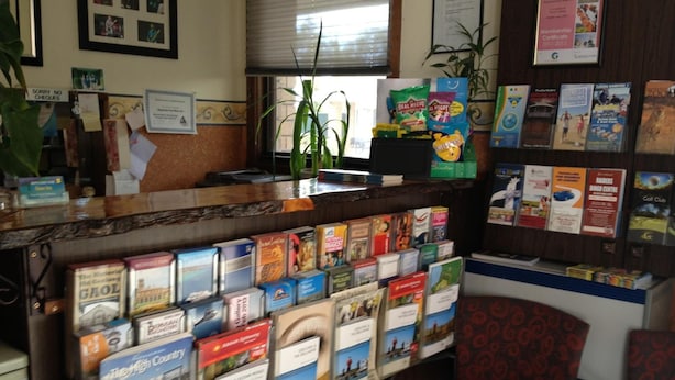 A reception desk with a variety of travel brochures and a membership certificate on the wall. - Rippleside Park Motor Inn (Drumcondra)