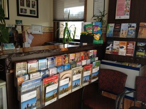 A reception desk with a variety of travel brochures and a membership certificate on the wall.