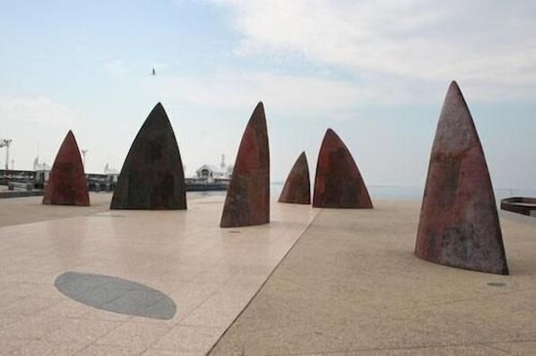 Une série de grandes sculptures triangulaires en pierre, disposées en rangée sur une surface pavée.