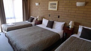 Une chambre d’hôtel avec deux lits simples et un lit double.