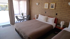 A hotel room with a large bed, a small table with chairs, and a window with curtains. - Rippleside Park Motor Inn (Drumcondra)