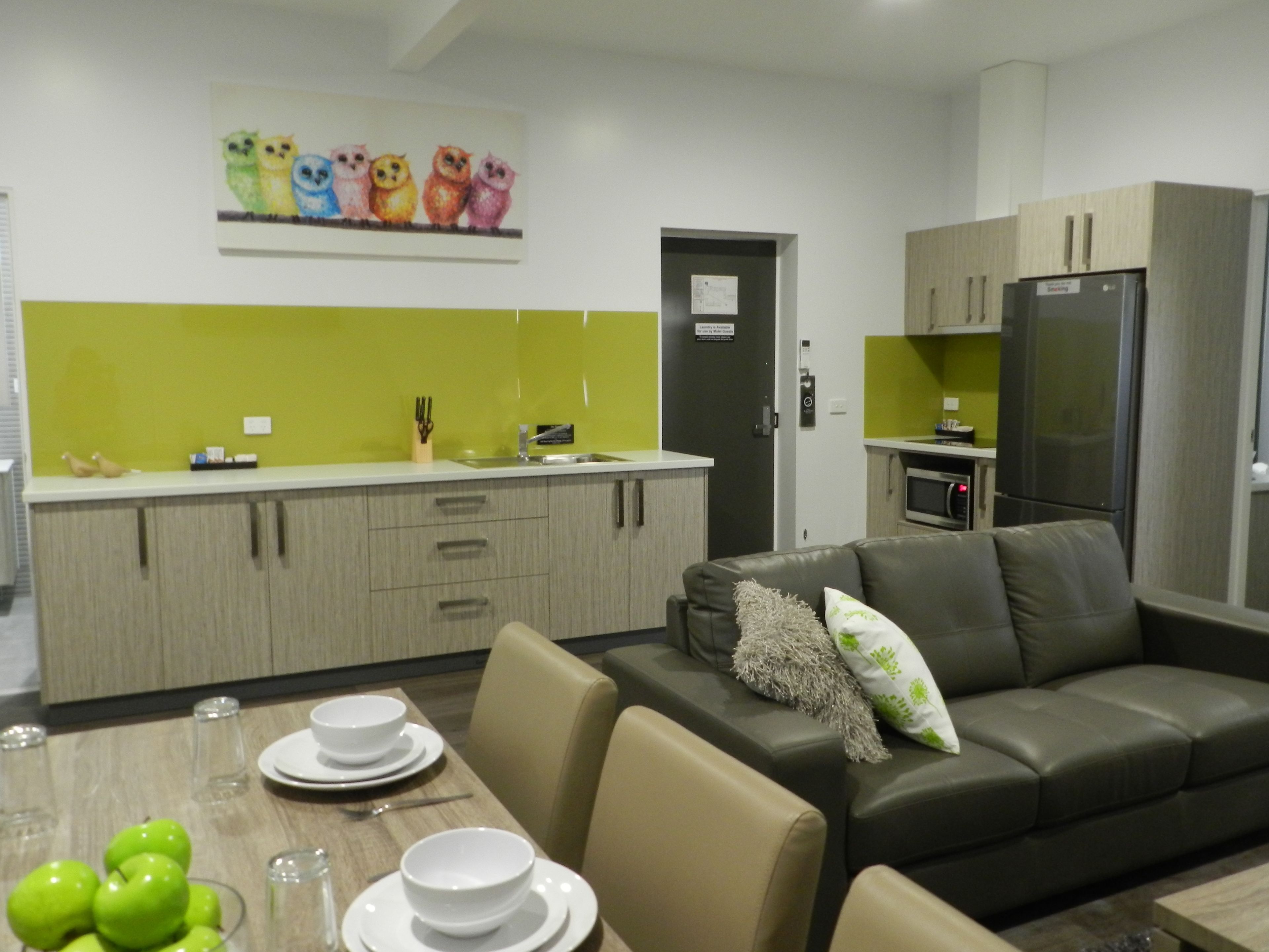 Una cucina moderna con zona pranzo, un divano e un quadro con gufi appeso al muro.