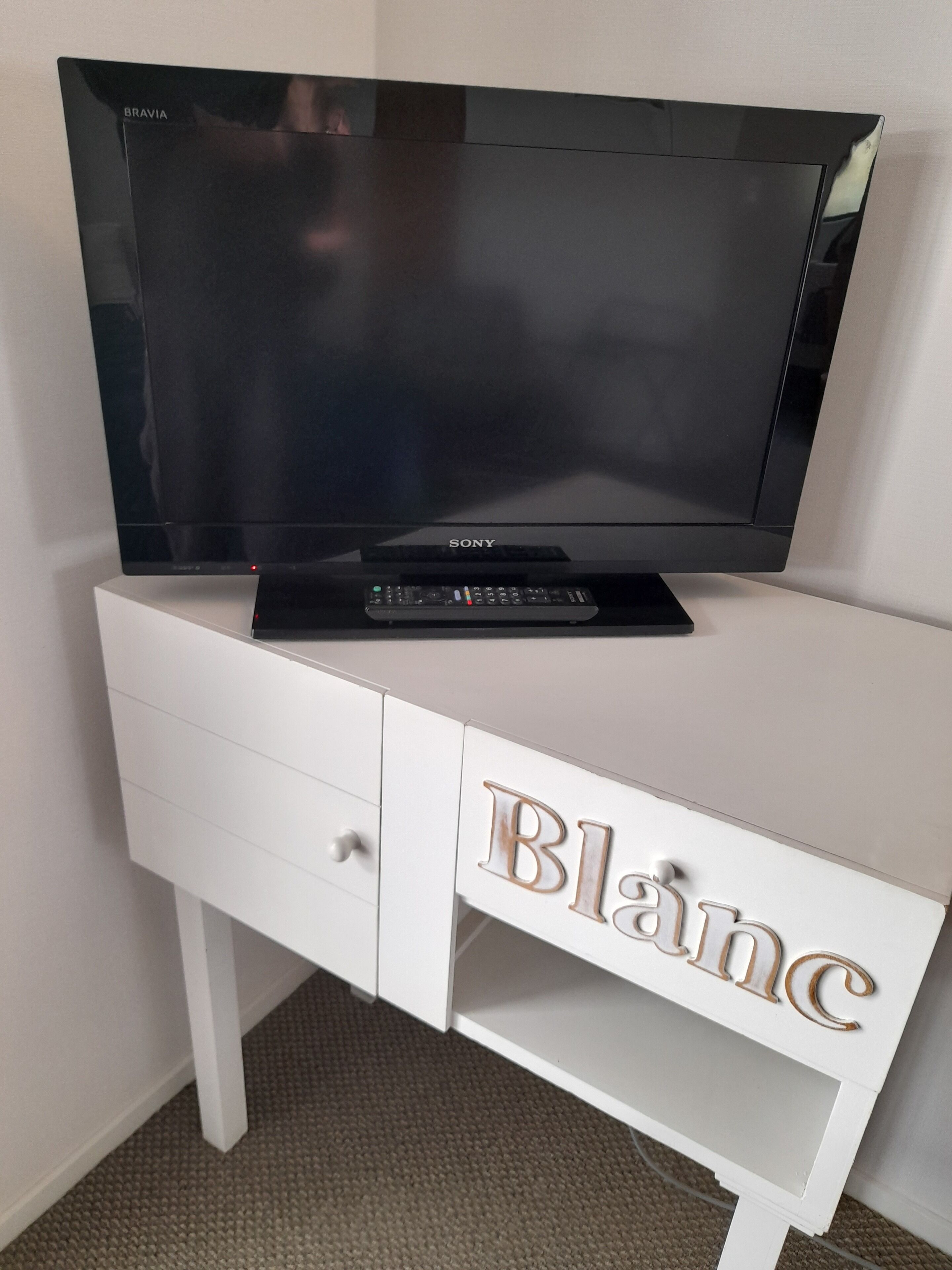 Un televisor sobre un mueble blanco con un control remoto.
