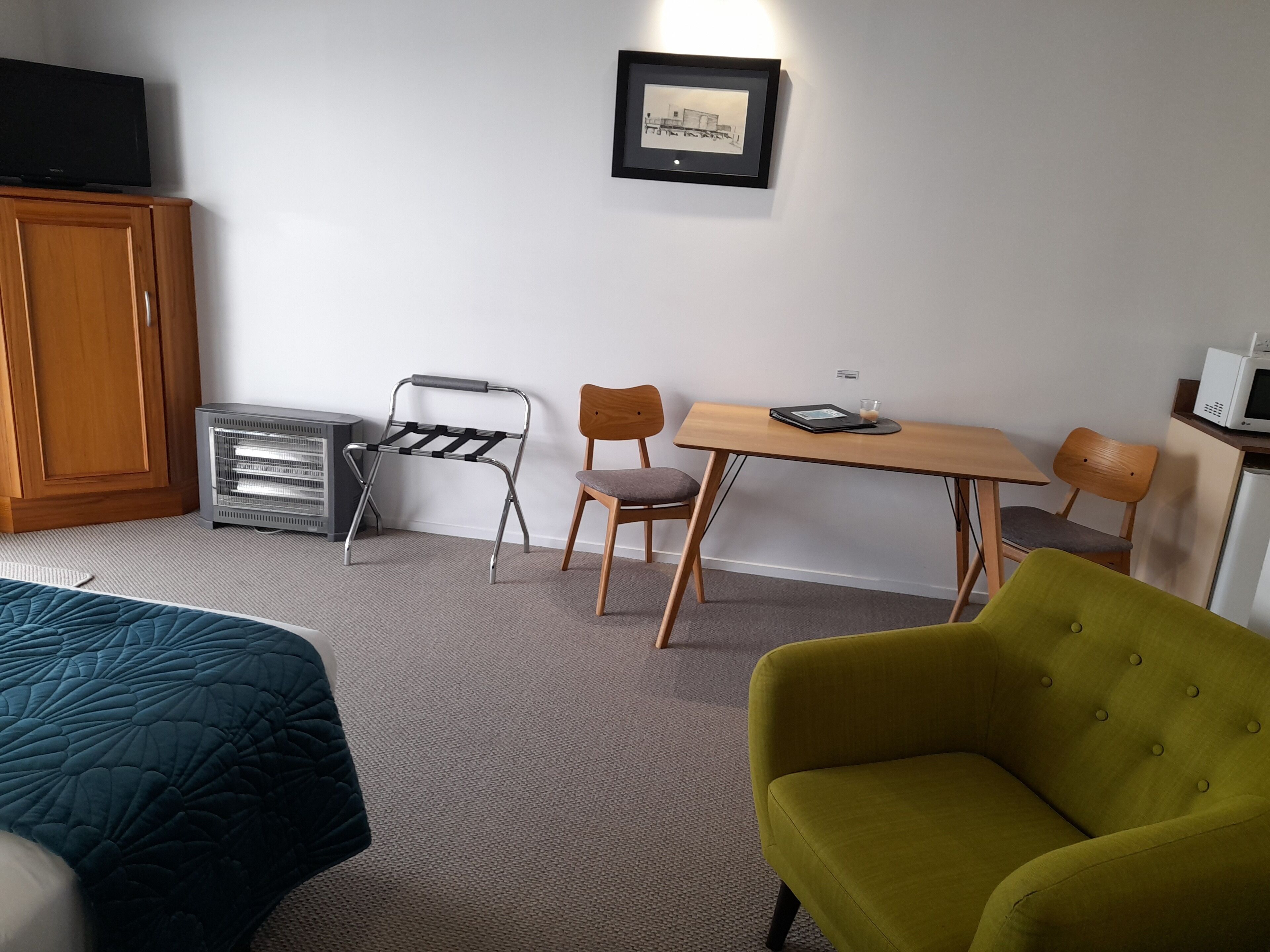 Een hotelkamer met een bed, een bureau, een stoel, een magnetron en een kast.