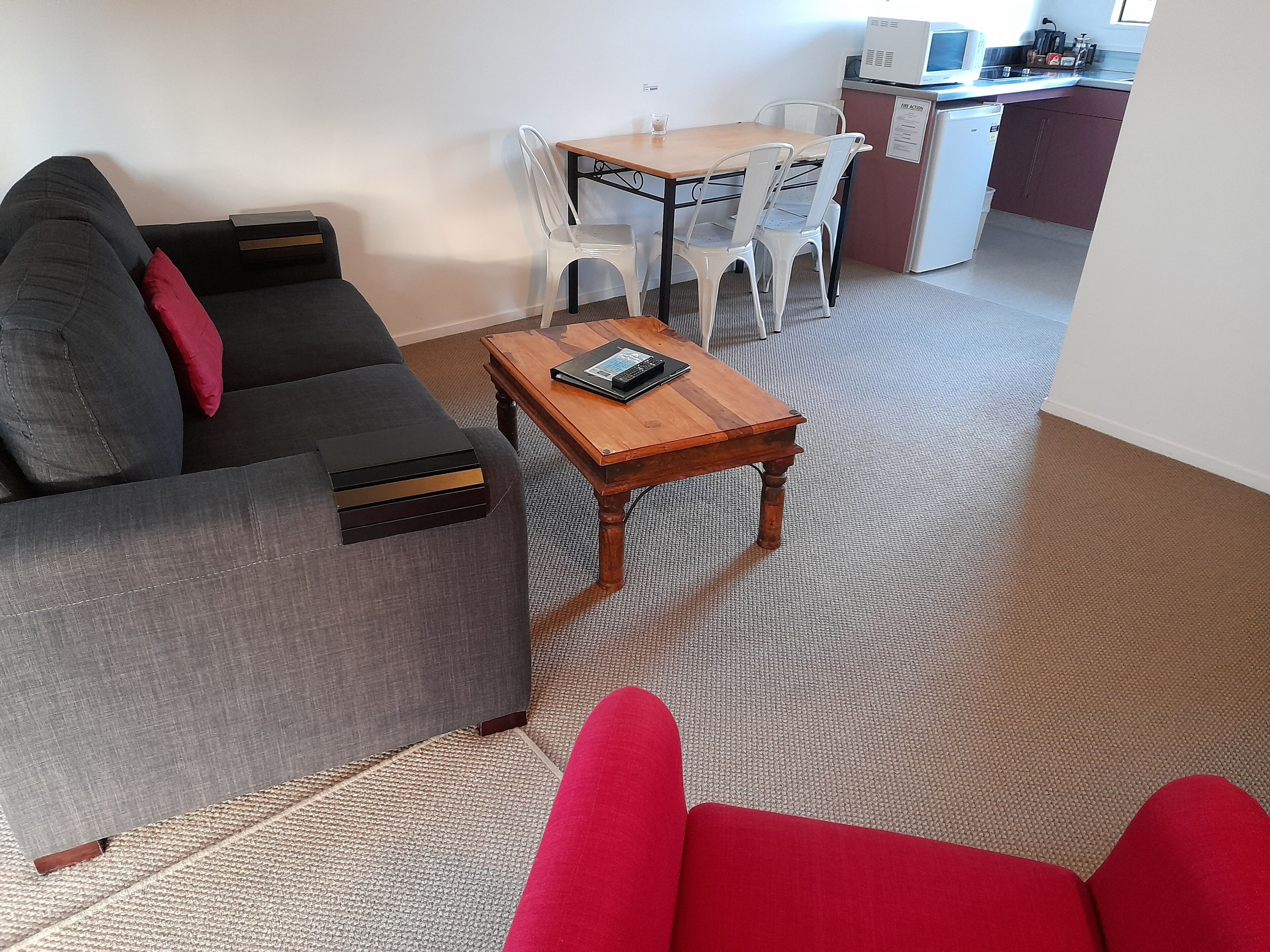 Ein Wohnzimmer mit grauem Sofa, einem Holztisch und einem Essbereich mit Tisch und Stühlen.