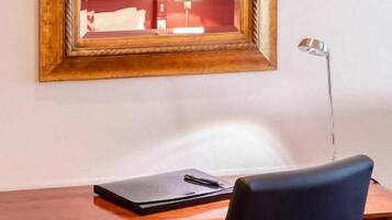 A wooden desk with a black chair, a lamp, and a laptop.