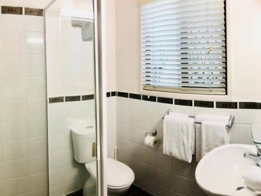 A bathroom with a glass-enclosed shower, a toilet, and a sink with a mirror.
