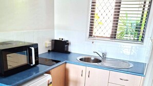 A compact kitchen with a microwave, toaster, sink, and cabinets. - Central Studio Accommodation (Gladstone)